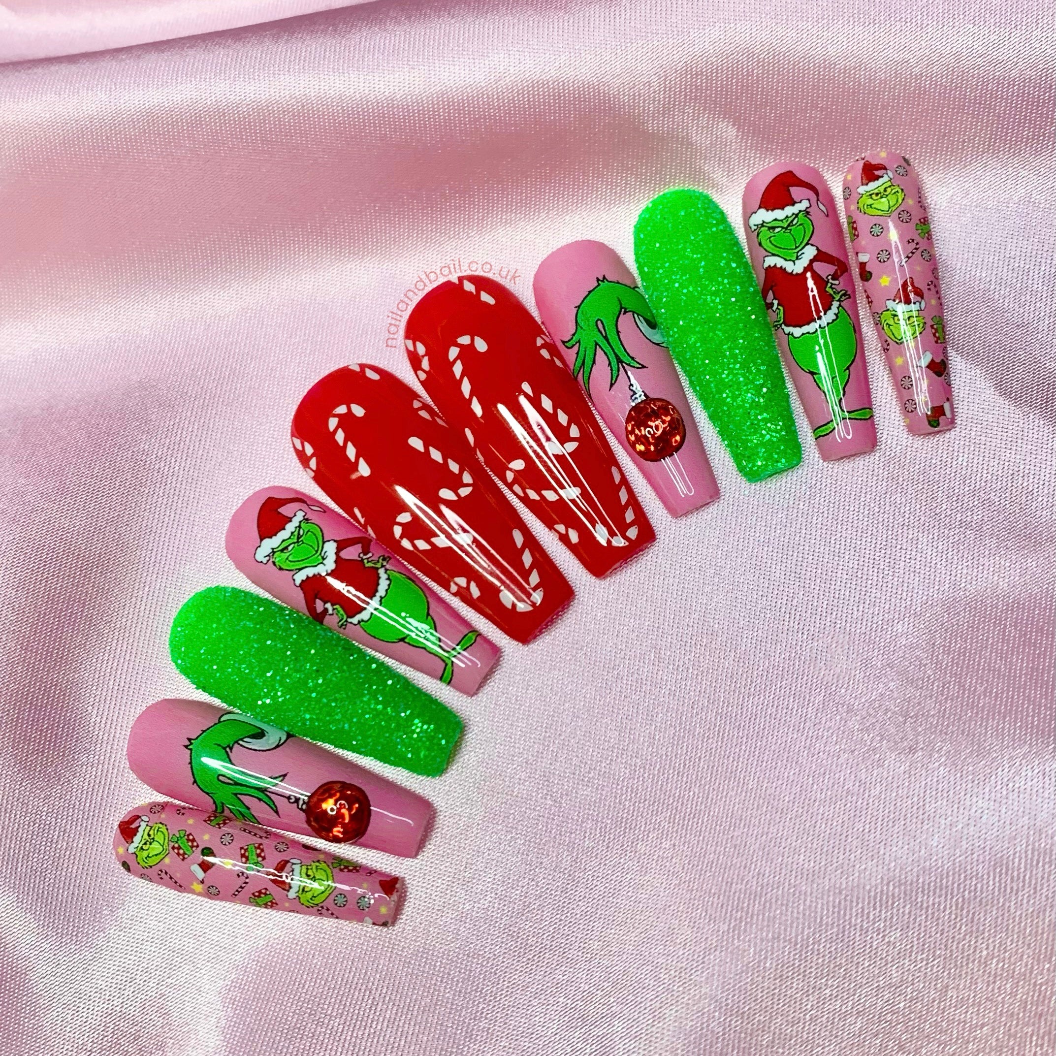 Grinch-inspired Christmas nail art on bold festive pink press-on nails