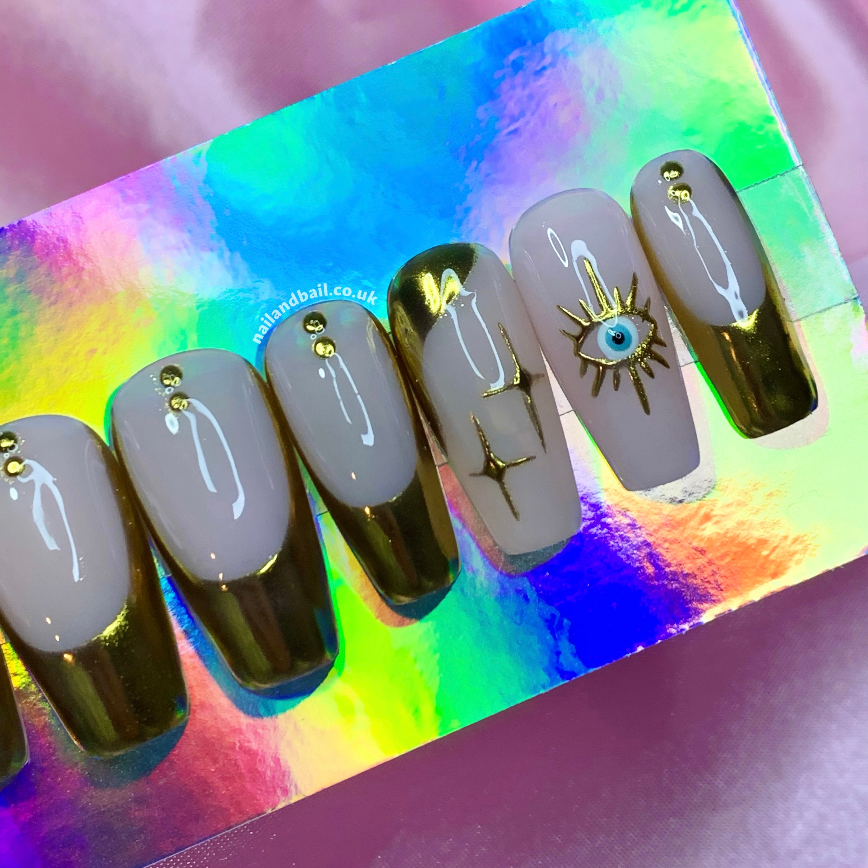 Unveiling our Golden Gaze Press On Nails: Where elegance meets mystique. Crafted to steal the spotlight, these nails redefine chic. With delicate nude bases and lavish gold French tips, your hands exude opulence. Adorned with gold stars and captivating evil eyes, your style becomes a story. Choose your fit from various shapes. Handcrafted with love, these nails are art to flaunt. Elevate any moment with a touch of luxury. Step into pure femininity. Order now, let your fingertips mesmerize! 