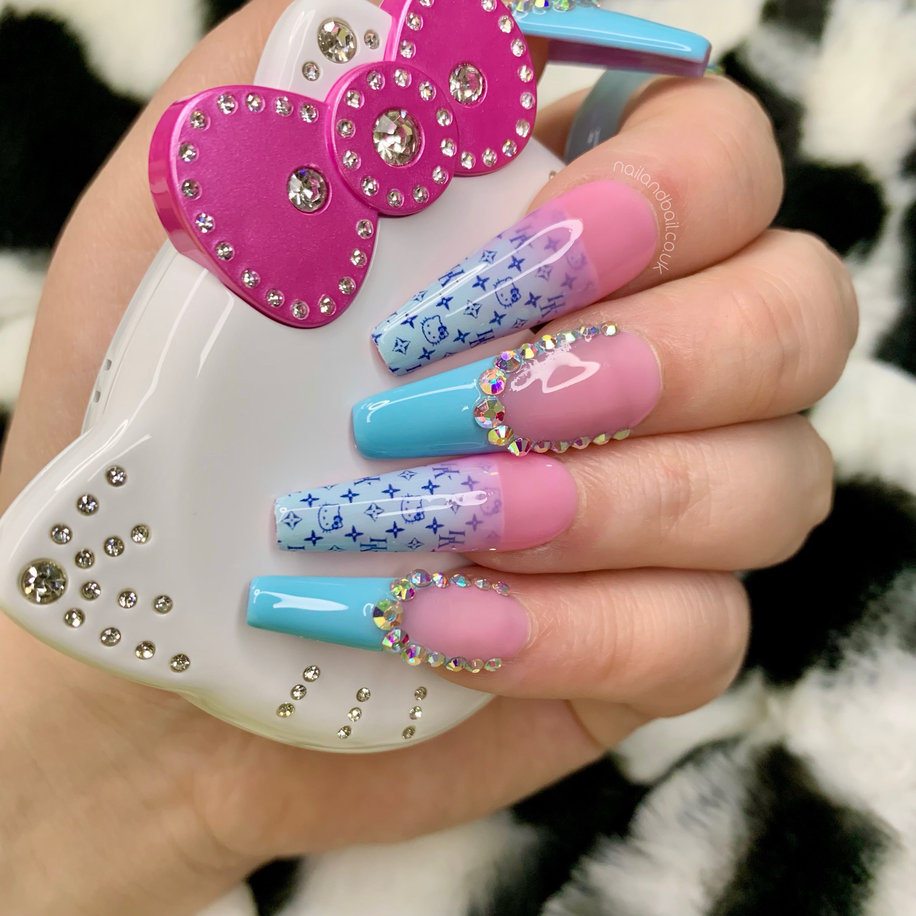 Nude pink press-on nails with baby blue French tips, crystals, and deep blue kitty-inspired nail art