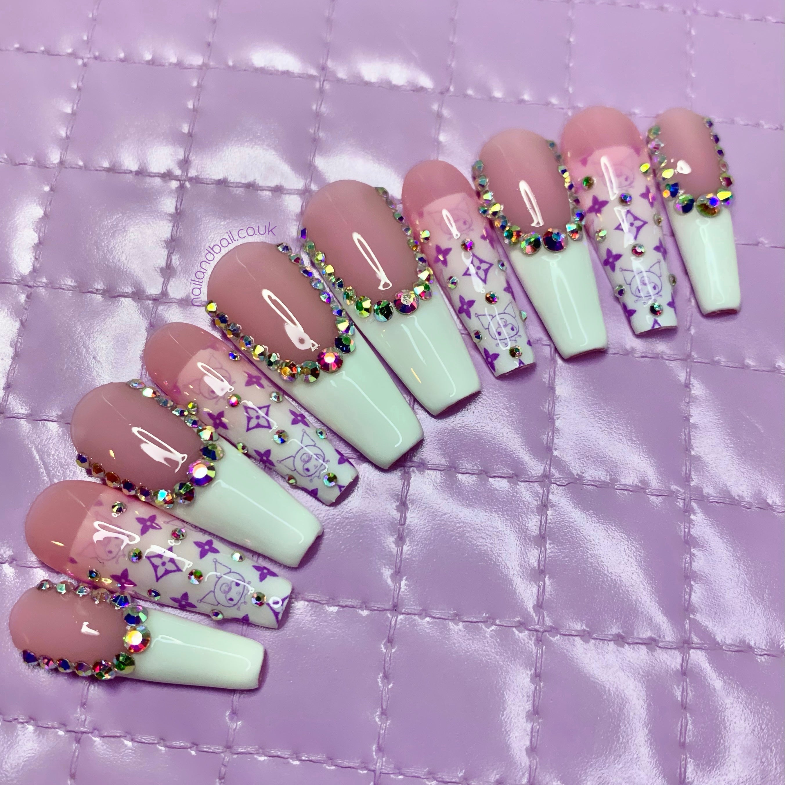 Kuromi-inspired press-on nails with nude pink French tips, ombré nail art, crystals, and purple designer-style details