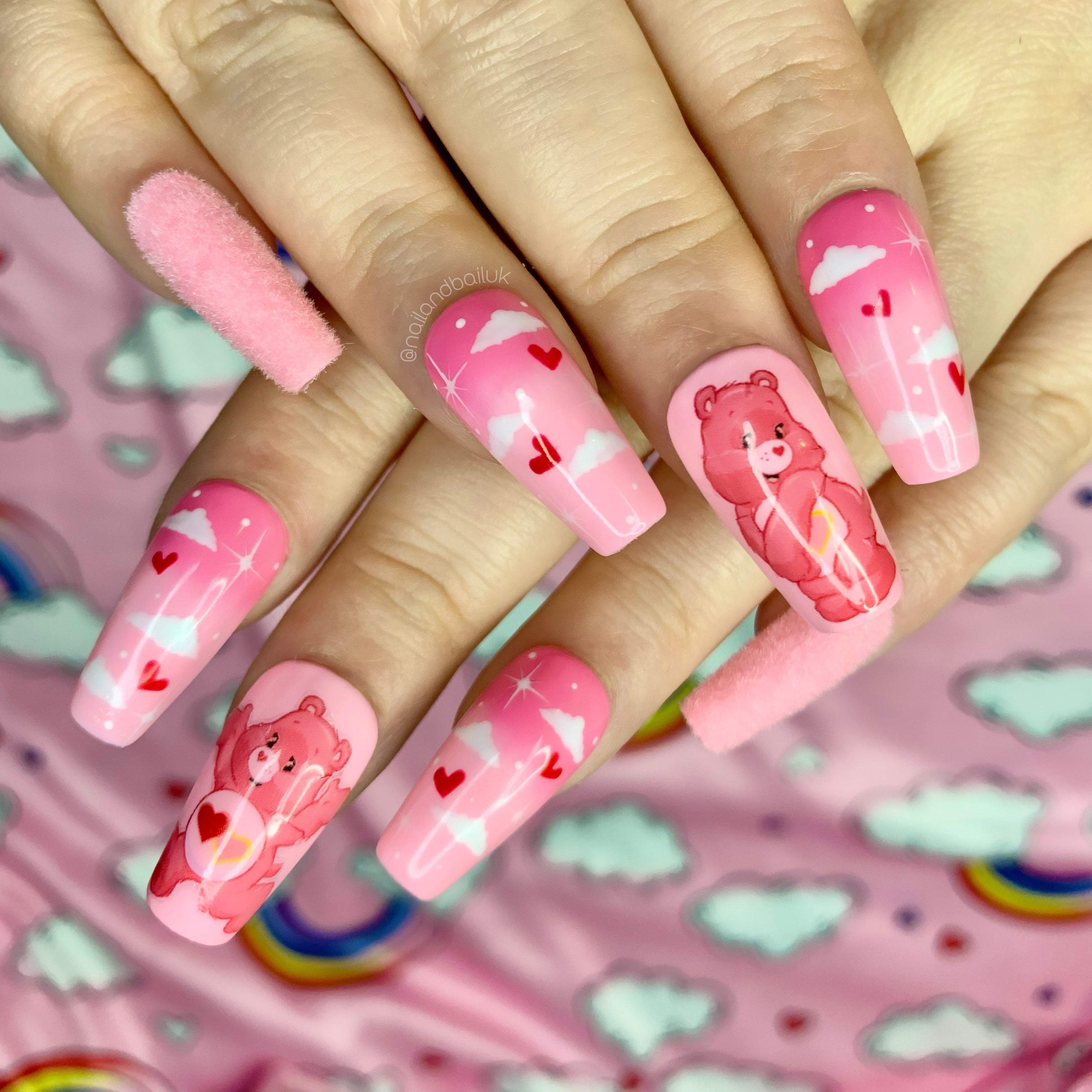 Pink fluffy press-on nails with Love A Lot Bear artwork, ombre clouds, hearts, and stars