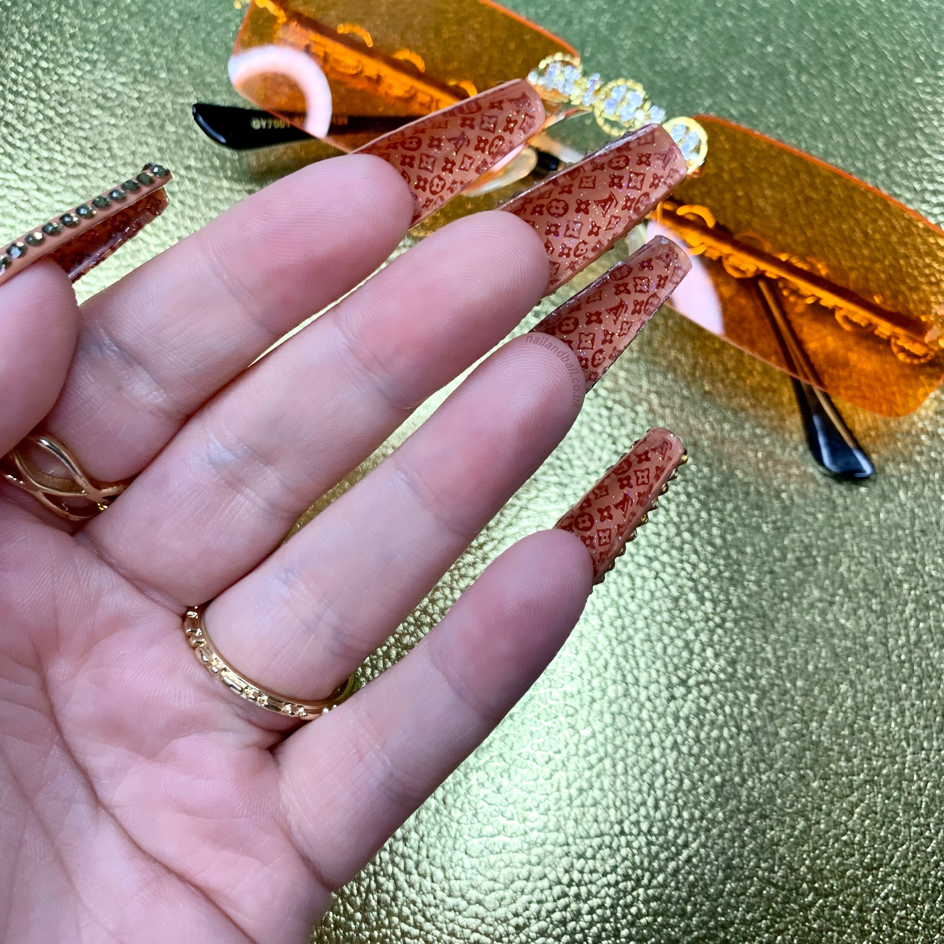 Luxury-inspired brown press-on nails with hidden artwork beneath the nails and crystal embellishments