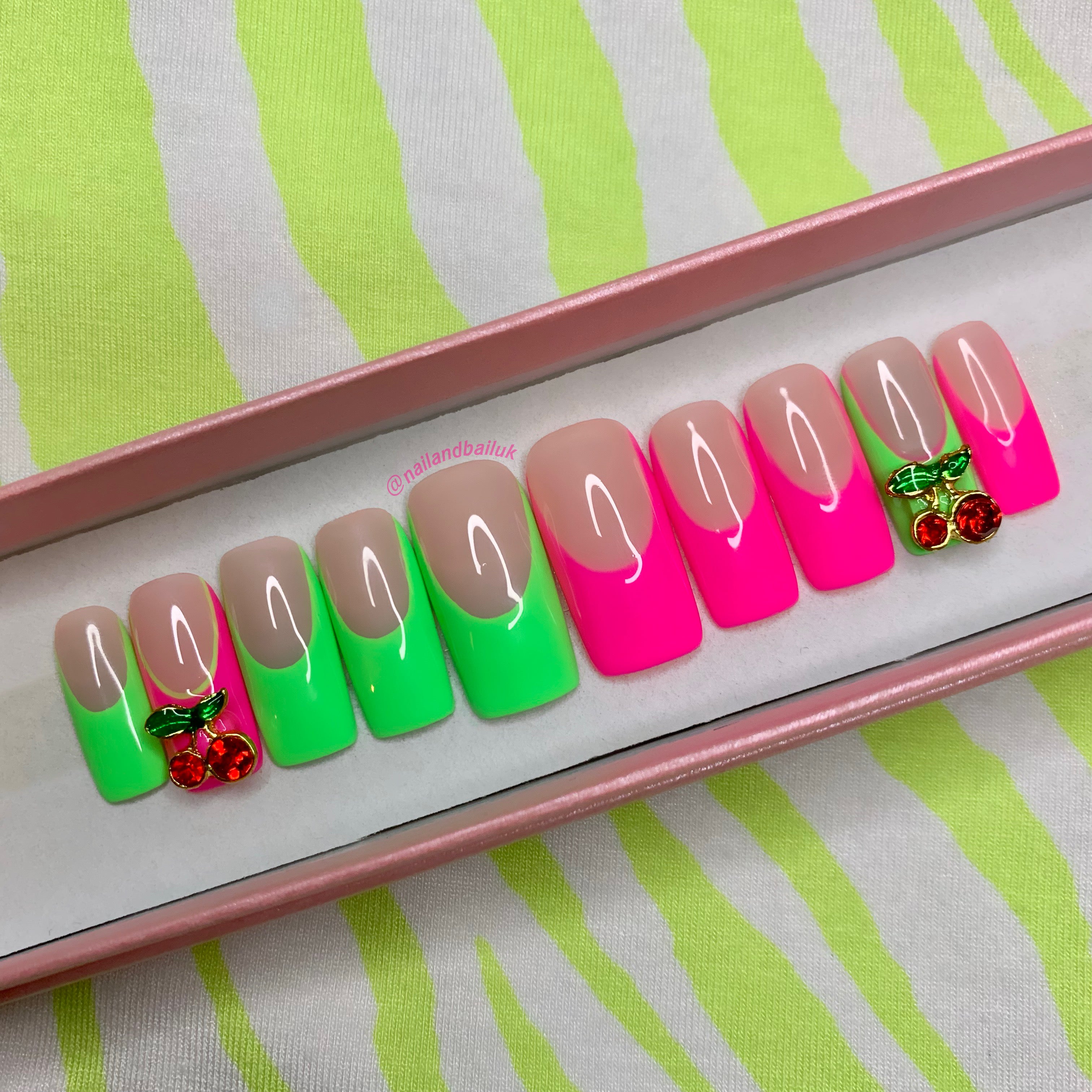 Neon green and pink French tip press-on nails with cute cherry charm accents