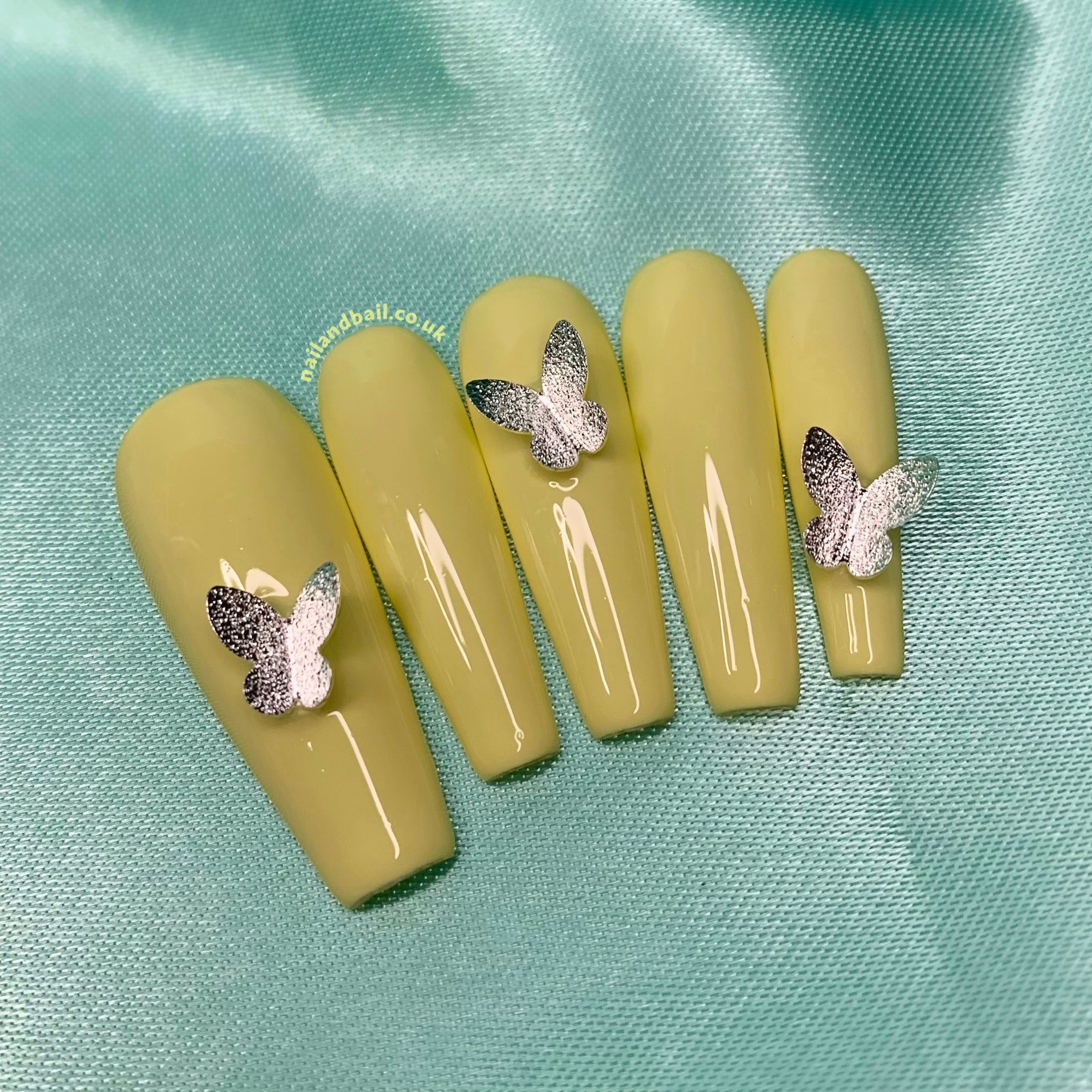 Pastel yellow press-on nails with elegant butterfly-inspired details