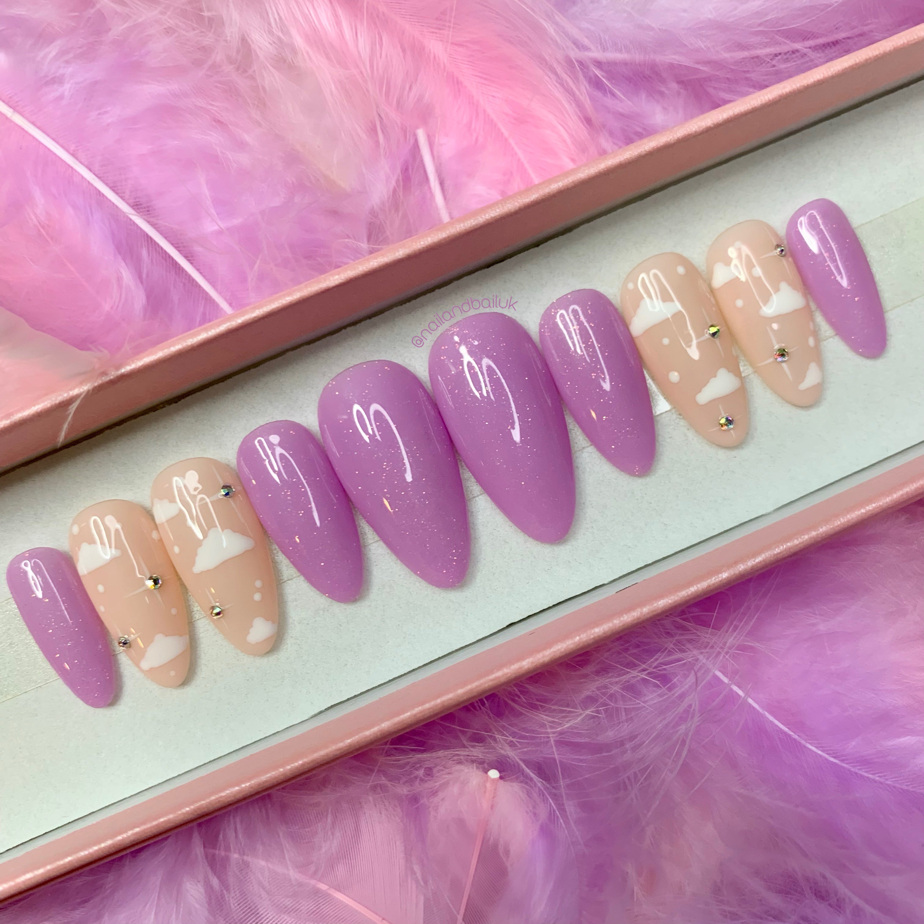 Pastel purple glitter press-on nails with cloud nail art, crystal stars, and glossy finish