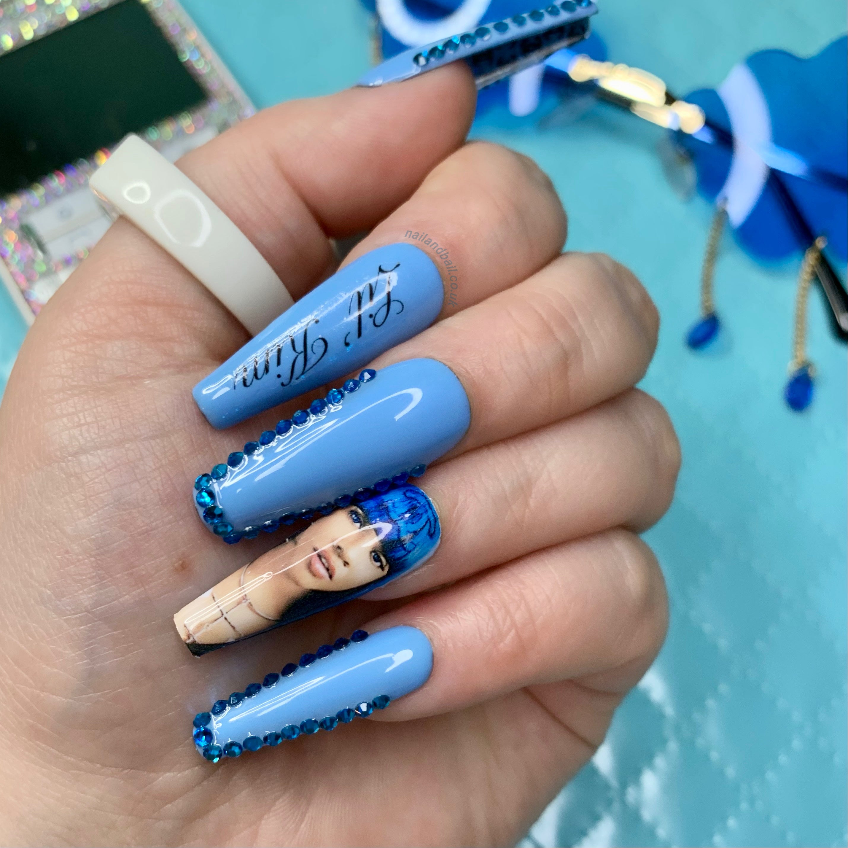 Blue glitter press-on nails with Lil’ Kim-inspired nail art, crystal embellishments, and hidden designer-inspired detailing