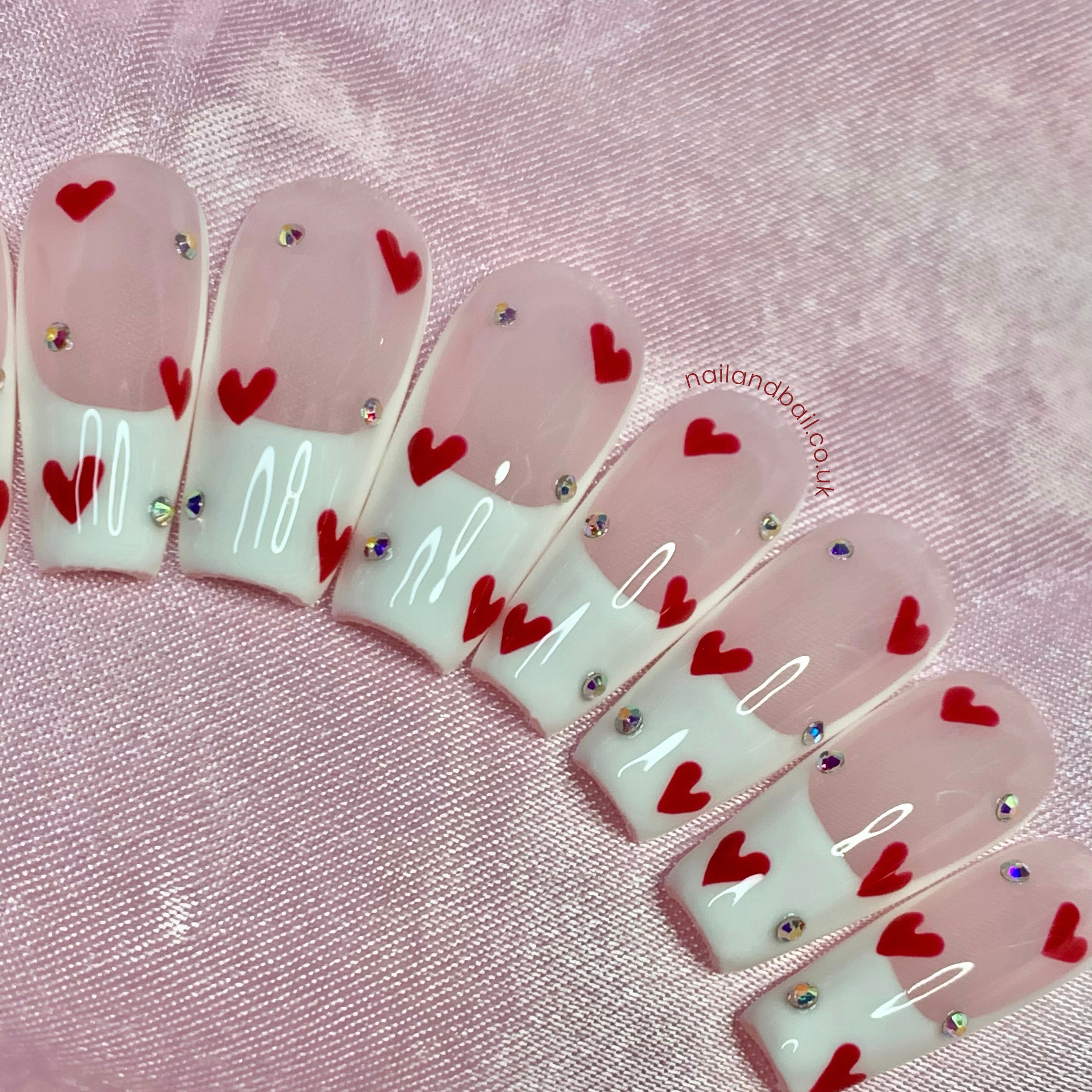 Red heart nail art on nude and white French tip press-on nails