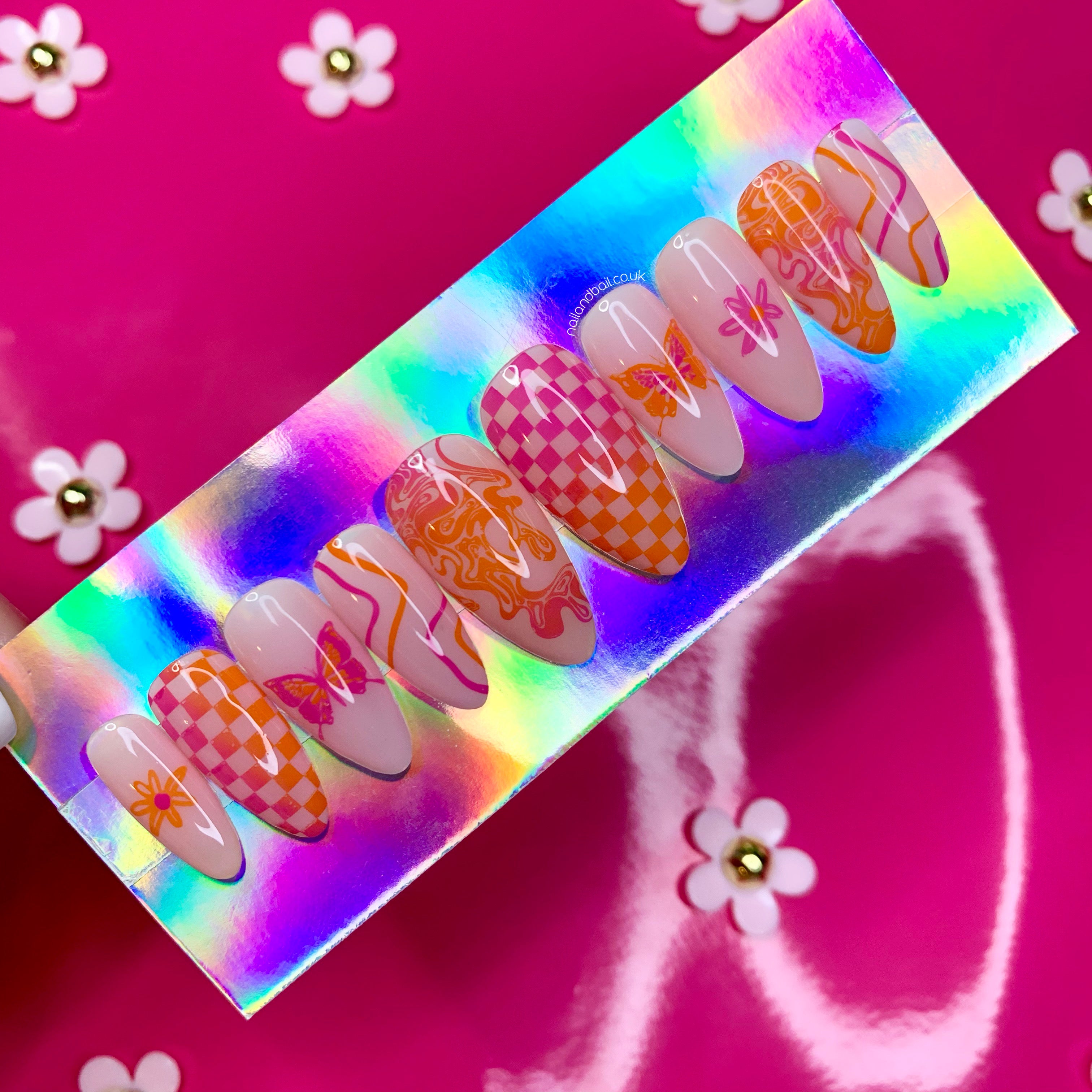 Summer-inspired press-on nails with orange flowers, colourful butterflies, and pink orange swirl nail art